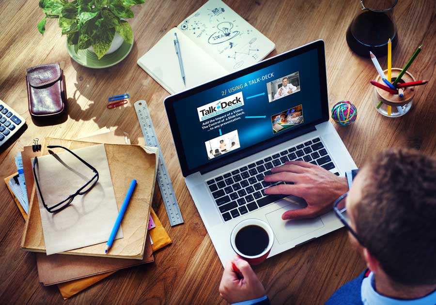 Close-up of man using laptop with slide titled “Using a Talk-Deck,” featuring visuals and arrows instead of bullet points; Talk-Deck logo below.